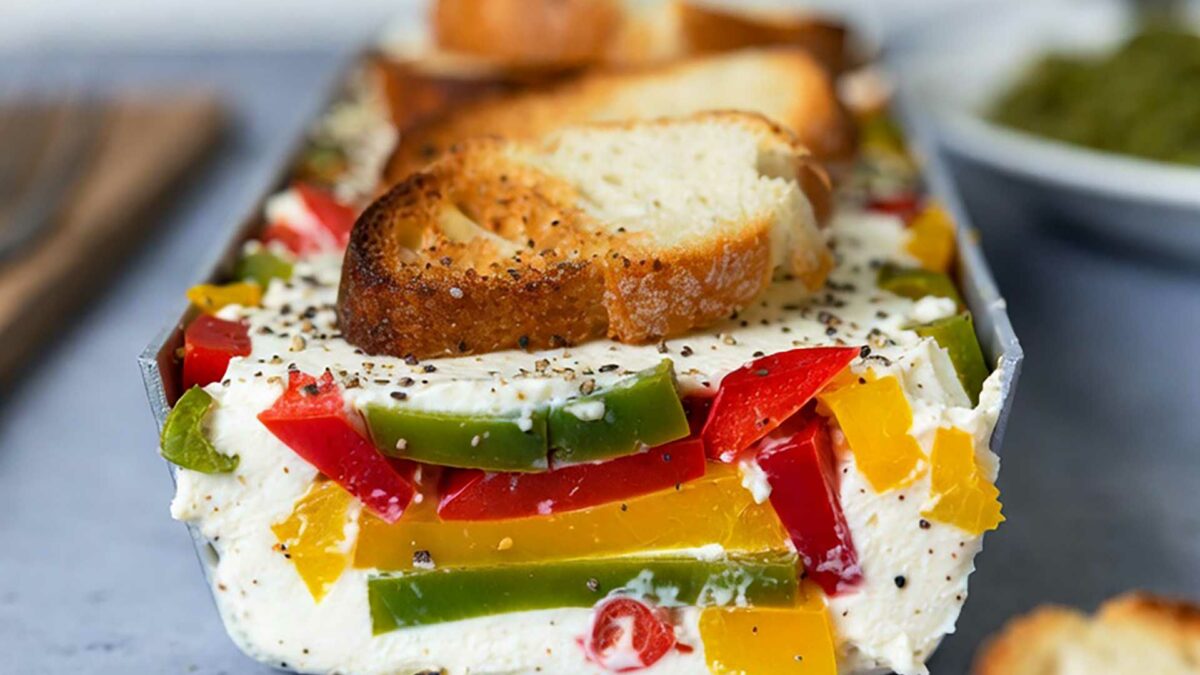 Terrine tricolore aux 3 poivrons coupée en tranche montrant les couches jaunes, vertes et rouges